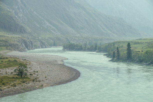 美丽的雾山景观和宽阔的山河。深绿色的阴森风景，大山河在薄雾中。阴雨天气，大山里的大河大气观。图片下载