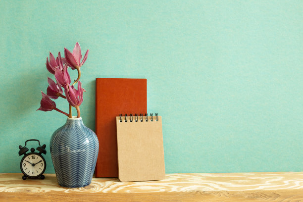 笔记本，时钟，木桌上的花。绿色背景。工作和学习场所图片下载