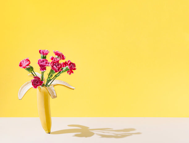 创意的布局，香蕉水果和自然花卉花束在柔和的沙子背景。女性主题的礼物。图片下载