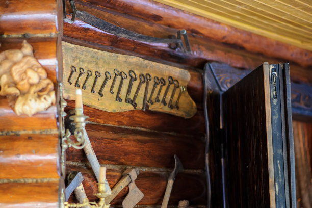 这张照片是一个带有不同尺寸的铁键和几把小斧头的面板，装饰在一个有木墙的餐厅里图片下载