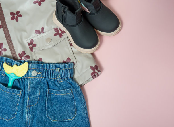 儿童牛仔裤，夹克口袋里有一个玩具和鞋子，街头儿童服装，时尚的服装特写在一个粉红色的背景图片下载