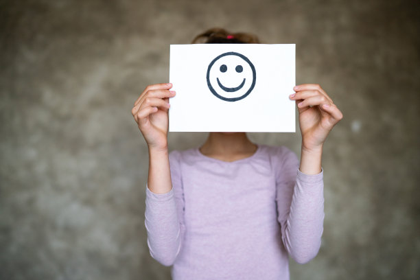 孩子抱着笑脸画。快乐的情绪。图片下载