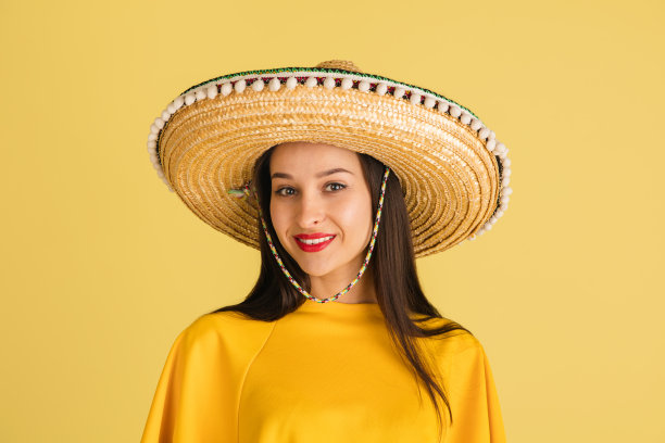 年轻美丽快乐的女孩戴着宽边帽，在黄色的背景上与世隔绝。图片下载