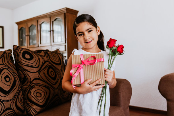 墨西哥城，拉丁小女孩在家里向妈妈祝贺，并送给她鲜花，祝她母亲节快乐图片下载