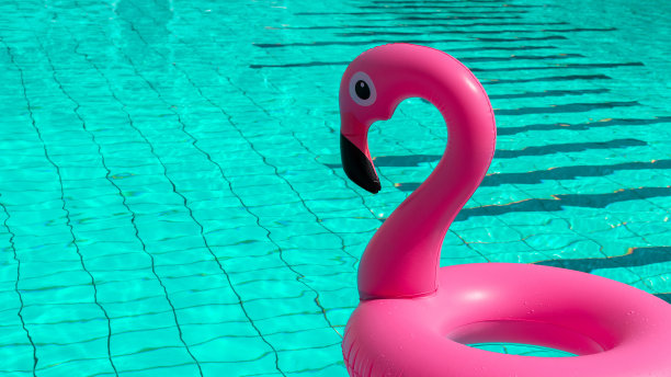 火烈鸟打印。粉红色的充气火烈鸟在游泳池的水为夏天的海滩背景。最小的夏天的概念。图片下载