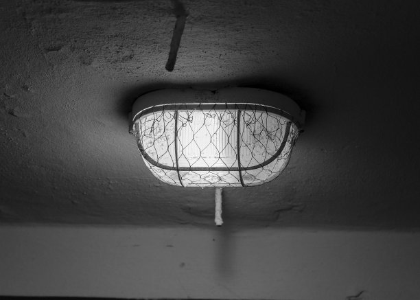 一盏用铁架盖着的旧灯，挂在一间黑暗的房间里。图片下载