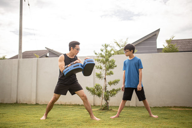 亚洲华人父亲在花园里训练儿子跆拳道。泰拳，武术图片下载