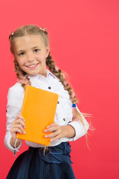 如果你需要知识，你必须读书。红色背景上抱着书的可爱小女孩，手里拿着书本知识的小女孩。知识日或9月1日。知识积累，复制空间图片下载