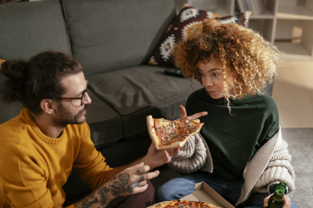 幸福的夫妇在家吃披萨。库存图片图片下载