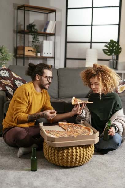 幸福的夫妇在家里吃披萨。库存图片图片下载