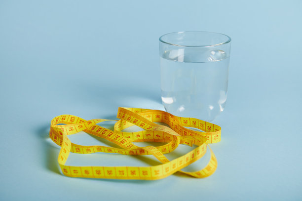一个装有水的杯子和一个卷尺，在蓝色背景上留出文字空间图片下载
