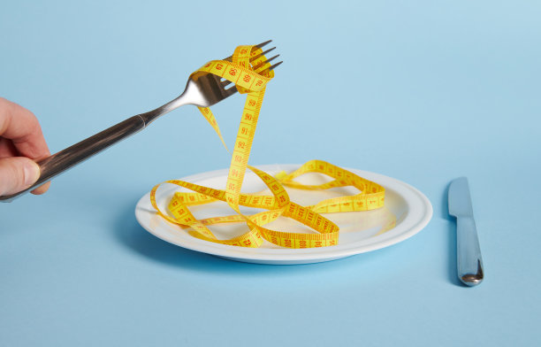 在空白的白色盘子上，手绕着叉子缠绕卷尺的特写图片下载