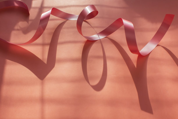 粉色背景上的粉色丝带。丝带装饰。节日装饰，婚礼，生日。磁带的影子。本空间图片下载