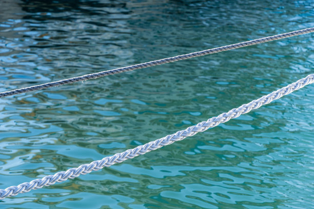 白色的海洋系泊绳映衬着碧绿的黑海海水。两根白色的航海线。索契海港白色绳索的背景图片。图片下载