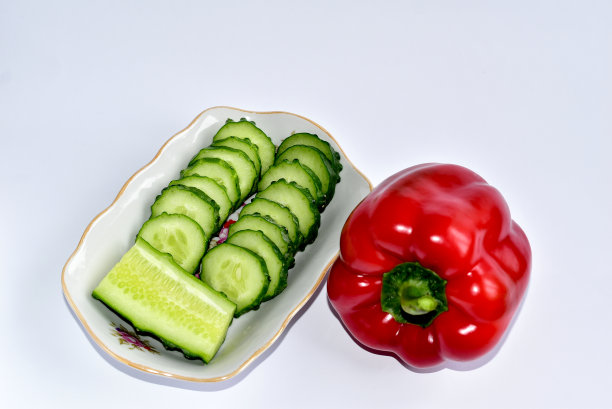 特写:切片的绿黄瓜和甜椒放在盘子上。图片下载