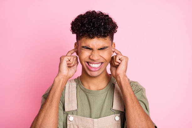照片肖像的非洲裔美国人堵住耳朵与两个手指孤立在柔和的粉红色背景图片下载