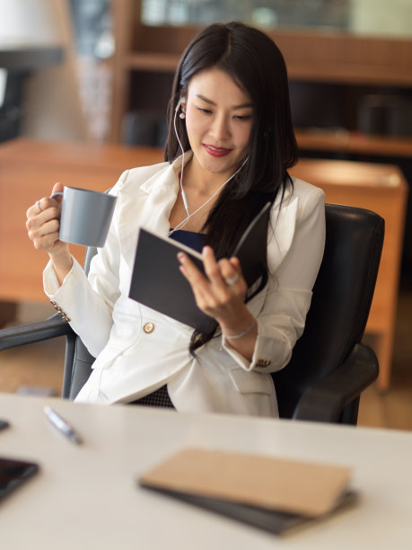 女商人用咖啡杯放松，用耳机听音乐和看书图片下载