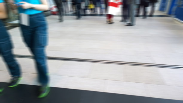 抽象模糊形象的人腿在展会的背景。商业场所。会议、会展中心。运动模糊。人群都很匆忙。入口大厅。图片下载