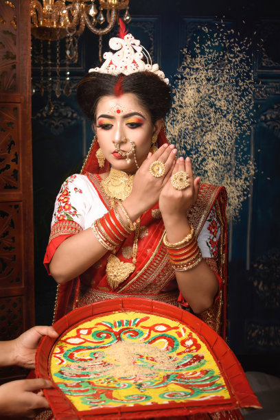 这是一幅美丽的印度妇女的肖像，她穿着传统的印度纱丽，戴着金首饰和手镯，在她的头上撒了一把米。孟加拉民族的婚礼。图片下载