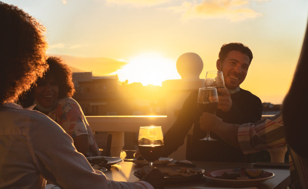 年轻的朋友与红酒在开胃菜日落时间在露台房子-饮料和食物的概念图片下载
