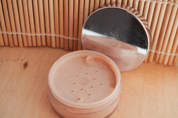 女人的化妆品。松散的矿物粉与粉刷的背景粉珠子和礼品盒。图片下载