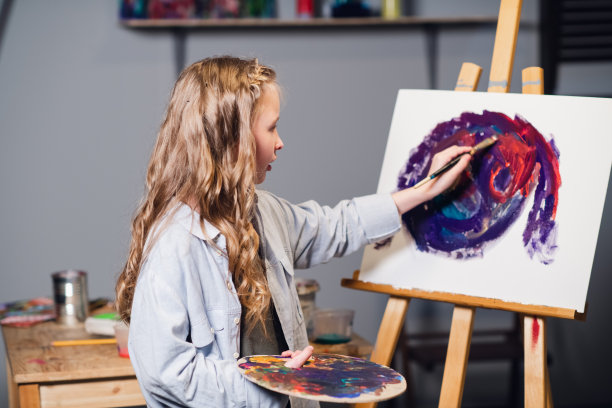 在艺术学校的第一节课上，一个小女孩学习画画，并在帆布上画了她的第一张油画图片下载