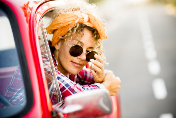 快乐愉快的年轻的成年妇女微笑，享受坐在她的红色时髦的汽车准备出发，开车去旅行旅行或度假快乐的生活方式女性人独立素材图片