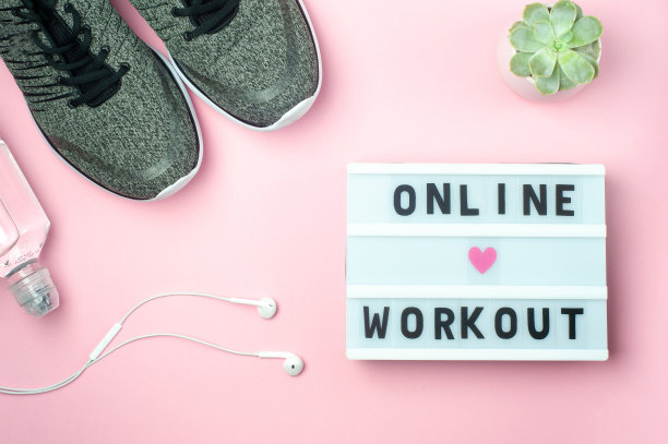 在线锻炼-文本显示灯箱粉红色的背景。平躺-运动鞋，一瓶水，白色耳机。体育的概念。图片下载