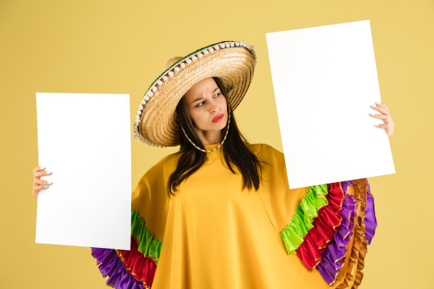 年轻美丽快乐的女孩戴着宽边帽，在黄色的背景上与世隔绝。图片下载