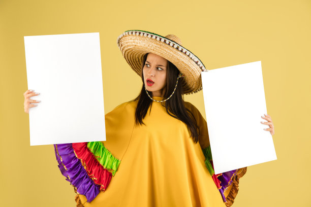 年轻美丽快乐的女孩戴着宽边帽，在黄色的背景上与世隔绝。图片下载