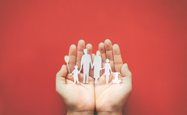 手握家庭剪纸上的红色背景。家庭日概念、寄养、家庭暴力、家庭学校、国际家庭日、世界精神卫生日、世界提高对自闭症认识日。图片下载