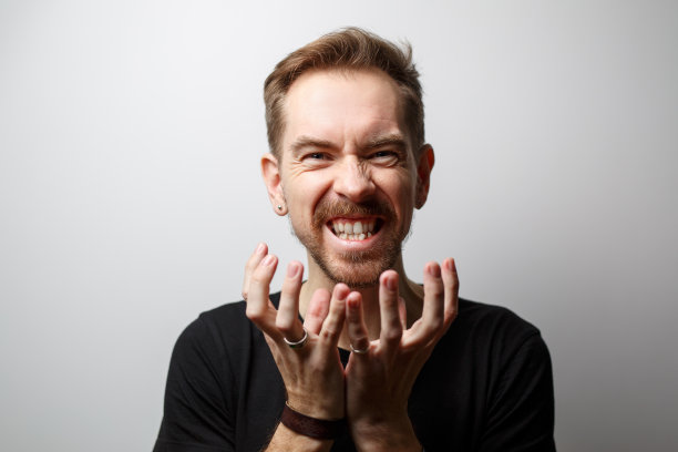 灰色背景上一名愤怒的年轻人的肖像。图片下载