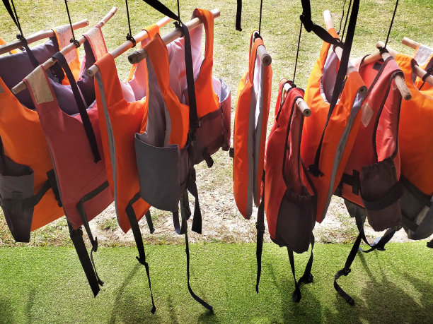 救生衣挂在晾衣绳上。彩色水上救生衣。轨道上的浮力夹克。水上运动安全配件。体育器材的模式。图片下载