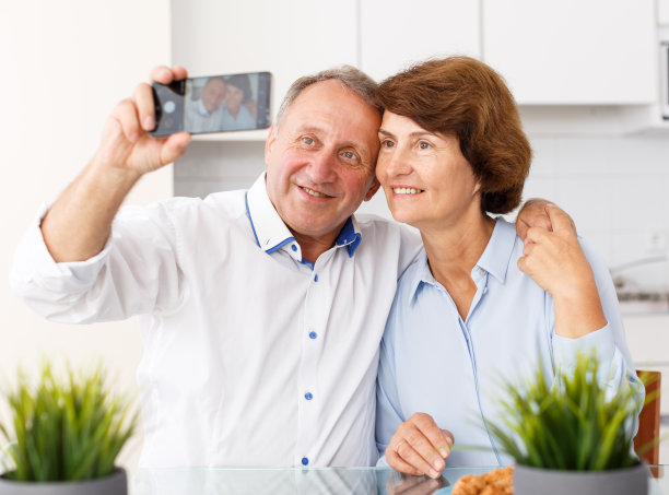 微笑的老年家庭夫妇在家里用手机自拍图片下载