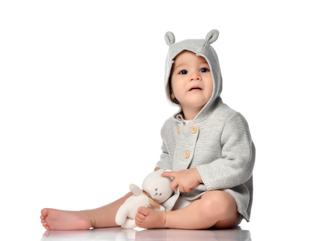 婴儿在针织运动衫与兜帽拥抱玩具兔子图片下载