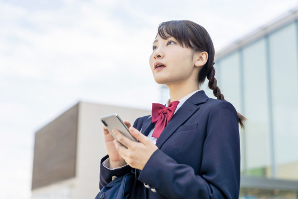 亚洲女高中生使用智能手机。素材图片