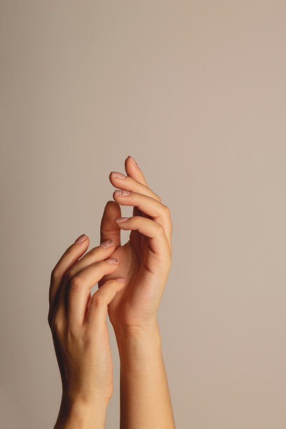 女人的手往上伸。以极简主义美甲在黑暗的背景图片下载