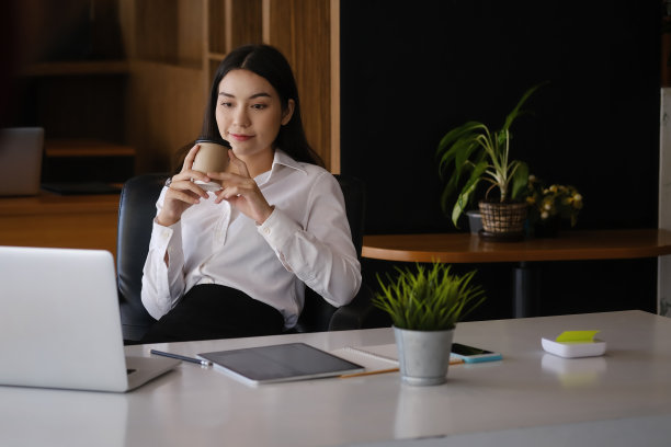 迷人的女商人在办公室喝咖啡休息。图片下载