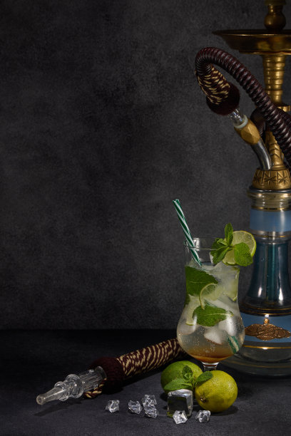 水烟和一杯莫吉托鸡尾酒，柠檬和冰在深灰色的背景。周末或假日聚会。水烟吧图片下载