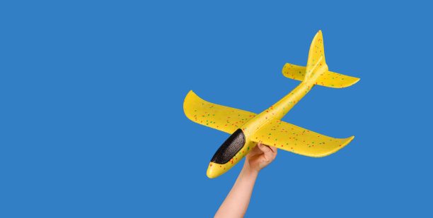 蓝色背景上的黄色玩具飞机。旅行的概念。图片下载