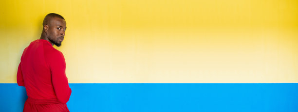 水平横幅的非洲运动男子与完美的身体站在前面的彩色背景图片下载