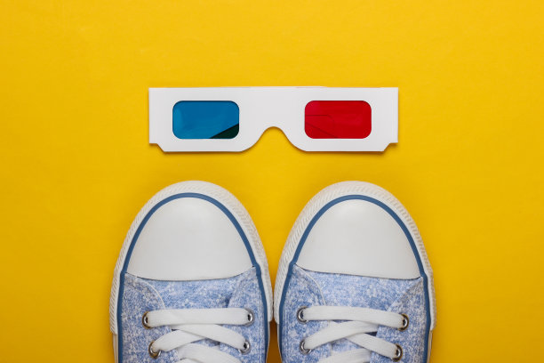浮雕一次性纸3d眼镜与旧学校风格的运动鞋在一个黄色的背景。前视图。复古80年代图片下载