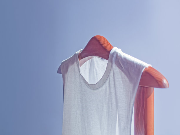 基本的白色衣服组成。一件棉质t恤放在一个木制衣架上。灰色的背景。图片下载