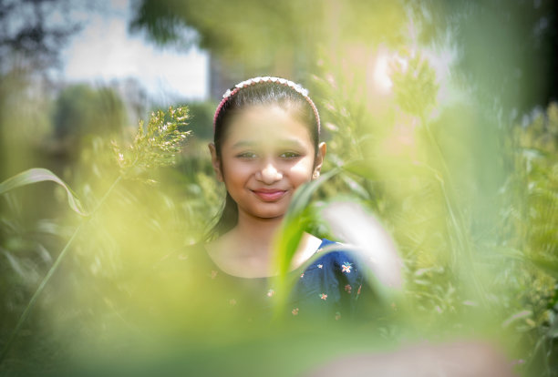快乐的印度少女站在高粱地里看着镜头。图片下载