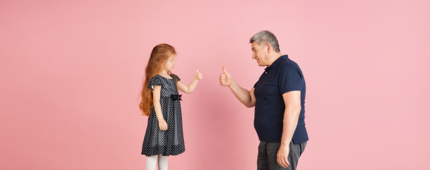两个人，男人和小女孩，爸爸和女儿孤立在粉红色的背景下。图片下载