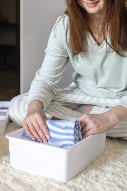 笑着把衣服卷起来的家庭妇女用近藤麻理惠的方法。把衣服放在柜子里图片下载