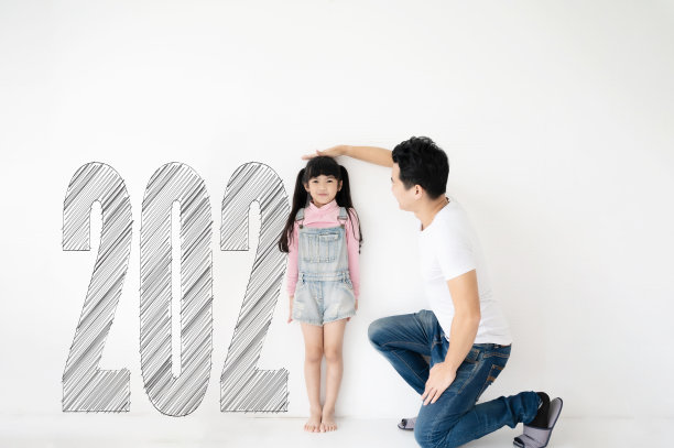 爸爸在白砖墙上测量女儿的身高增长，数字是2021年图片下载