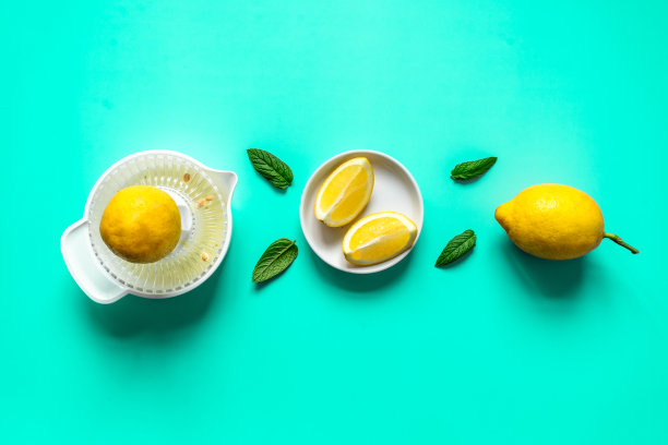 柠檬，柠檬挤压器和薄荷叶在一排薄荷背景图片下载