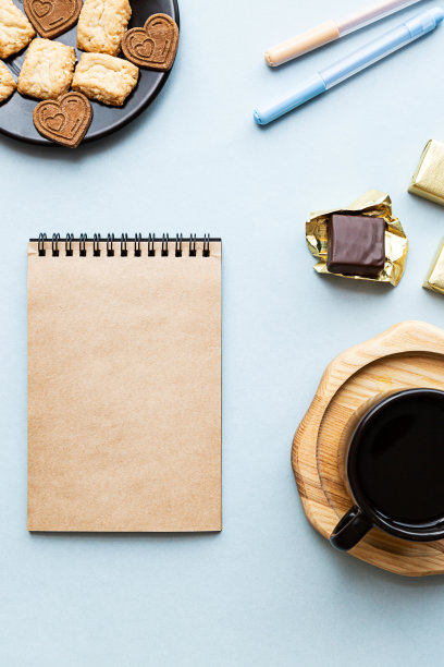 空白笔记本，办公用品，糖果和咖啡杯在蓝色的背景。教育、商业、规划或办公生活理念图片下载