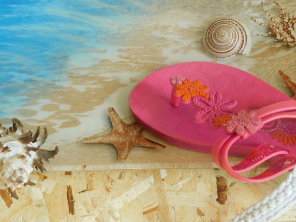 木桌上放着一张海岸的照片，上面放着女士的粉色凉鞋。图片下载